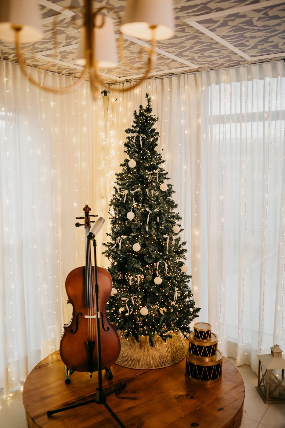 Árvore de Natal iluminada com um violoncelo apoiado ao lado e tambores decorativos