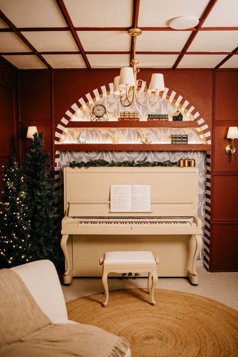 Piano claro diante de parede vinho com arco listrado e luminárias